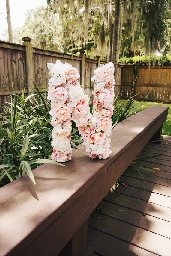 flowers are arranged in the shape of the letter n on a bench near some plants