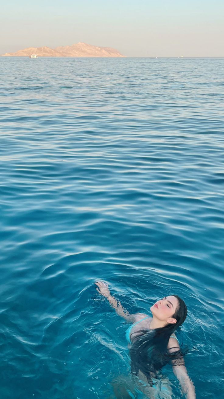 a woman floating in the ocean with her arms outstretched