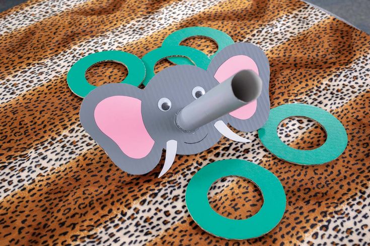 an elephant mask and some paper circles on a leopard print tablecloth with the number eight