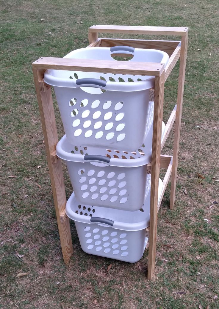 three laundry baskets stacked on top of each other in the grass next to a wooden rack