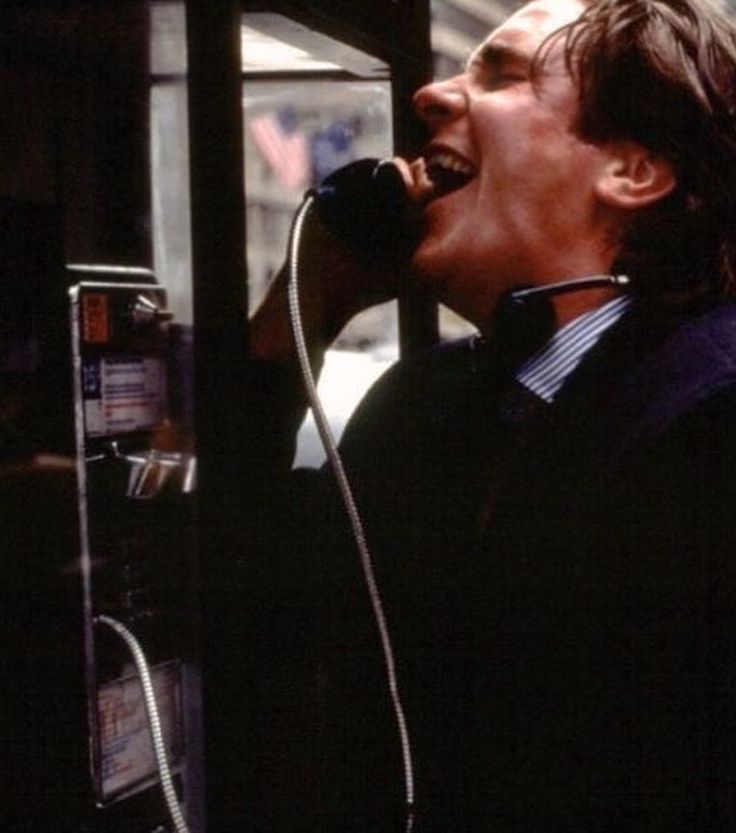 a man talking on a telephone while holding his mouth open