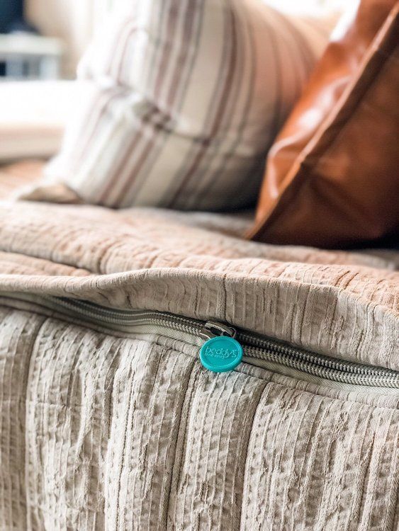 a close up of a bed with two pillows and a zipper on the pillow case