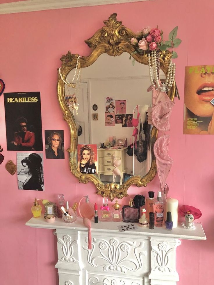 there is a vanity and mirror in this room with pink walls, white furniture and pictures on the wall