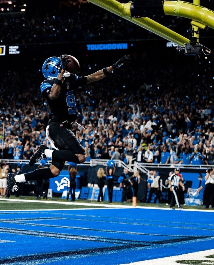 a football player jumping into the air to catch a ball in front of an audience