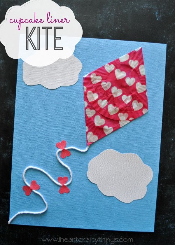 a kite made out of paper on top of a piece of blue paper with hearts