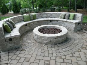 an outdoor fire pit surrounded by bricks and pillows