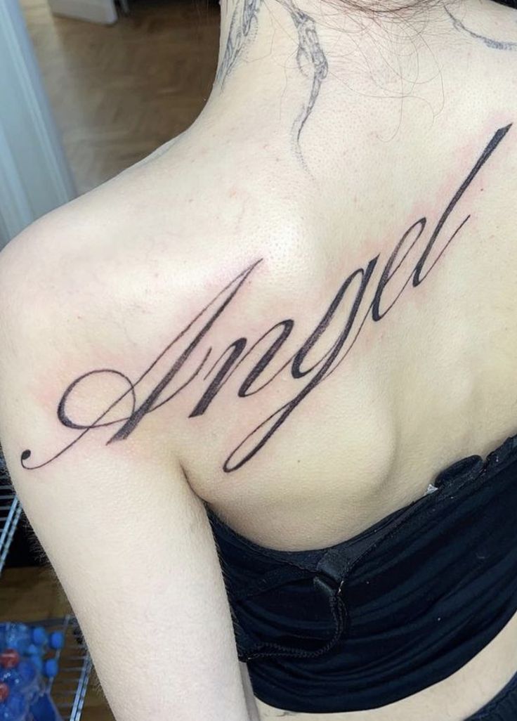 the back of a woman's shoulder with an angel tattoo on it that reads angel