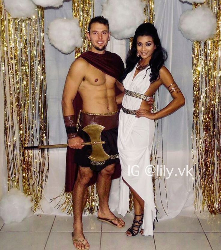 a man and woman dressed up in roman garb standing next to each other with gold sequins on the wall behind them