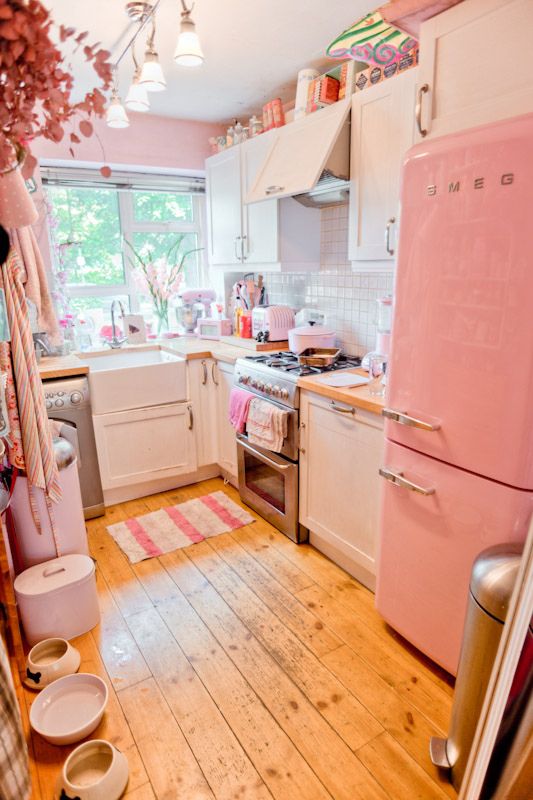 a pink refrigerator freezer sitting inside of a kitchen next to a stove top oven