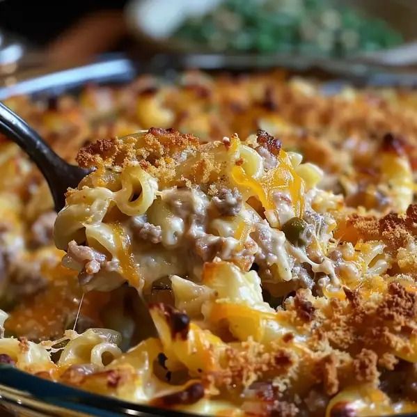 a casserole dish with sausage and cheese being lifted from the casserole