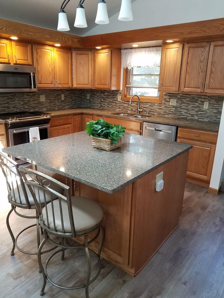 a kitchen with an island and three stools next to the counter top in front of it