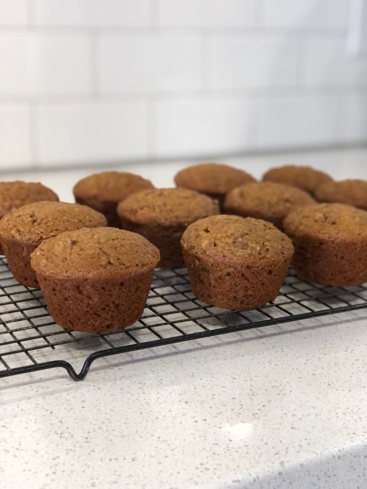 several muffins cooling on a wire rack in the middle of a kitchen counter