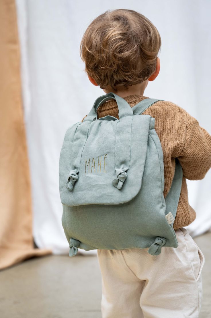 a little boy with a blue backpack on his back and the name natt written on it