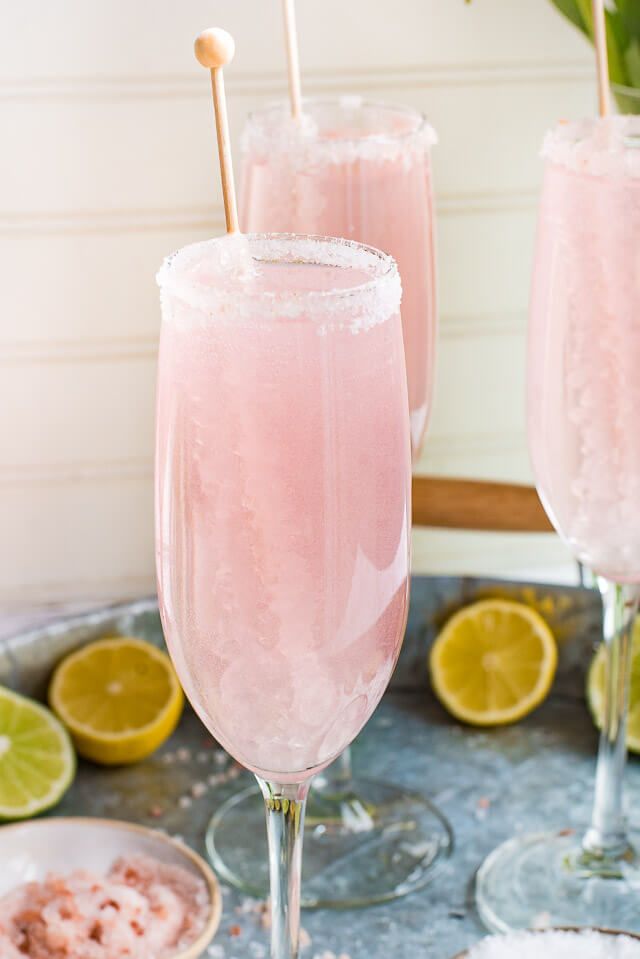 two glasses filled with pink lemonade sitting on top of a metal tray