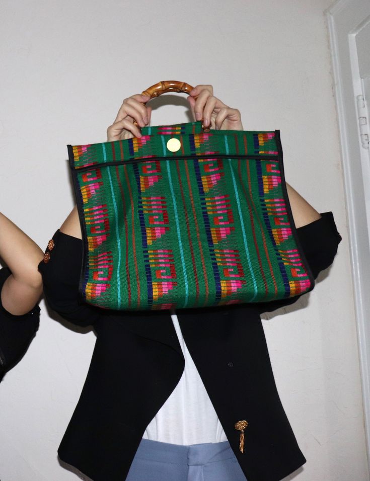 A unique roomy tote bag perfect for everyday use, the Nena bag is entirely made by hand in Spain. It is crafted in Cambaya fabric, a traditional Mexican cotton fabric made on wooden pedal looms, in Michoacán. This fun colorful bag is finished with a bamboo handle, and the interior is lined in black cotton fabric. Material: Cotton Cambaya fabric, bamboo handle HANDMADE IN SANTANDER, SPAIN Size: 16 x 15 x 5 in / 40,5 x 38 x 13 cms The Nena bag comes in a Cuckoo B cotton dust bag. Cuckoo B believes Black Cotton Fabric, Colorful Bags, Traditional Mexican, Bag Green, Bamboo Handles, Mexican Style, Green Bag, Black Cotton, Dust Bag