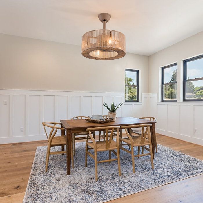 a dining room table with chairs and a chandelier hanging from the ceiling in front of two windows