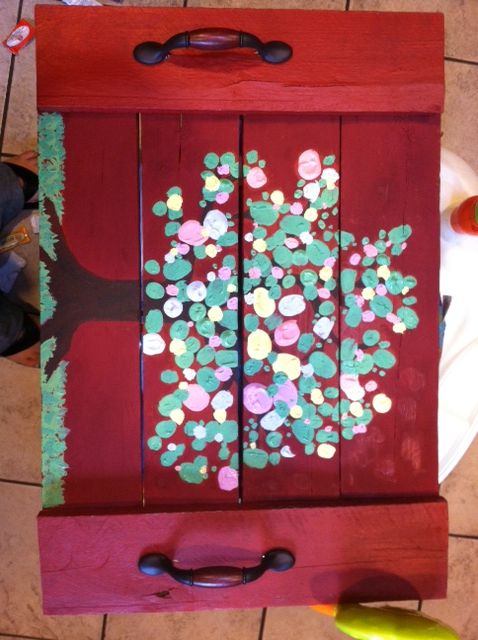 a wooden box with painted flowers on it sitting on the floor next to a plate