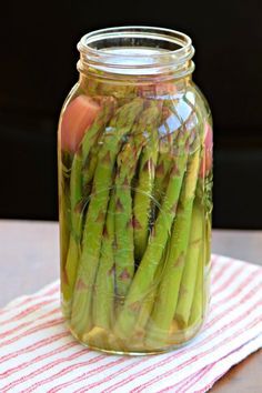 a jar filled with asparagus sitting on top of a red and white towel