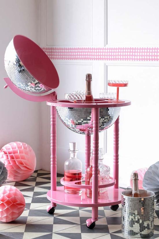 a pink bar cart sitting on top of a black and white checkered floor