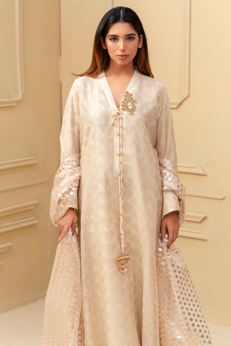 Expertly crafted from luxurious khaadi silk, this beige shalwar kameez boasts a stunning jamawar mesore dupatta and silk trousers. The hand sewn pearl details on the sleeves and neckline add a touch of elegance to this traditional ensemble. Elevate your style with this timeless piece. 3-Piece Suit Long Sleeve Cotton Silk Sherwani With Dabka Work, Elegant Cream Cotton Silk Traditional Wear, Festive Cream Cotton Silk Churidar, Cream Anarkali Churidar With Long Sleeves, Designer Cream Anarkali Set With Long Sleeves, Designer Cotton Silk Cream Salwar Kameez, Elegant Tussar Silk Straight Kurta, Elegant Tussar Silk Kurta With Chikankari Embroidery, Cream Cotton Silk Kurta For Eid