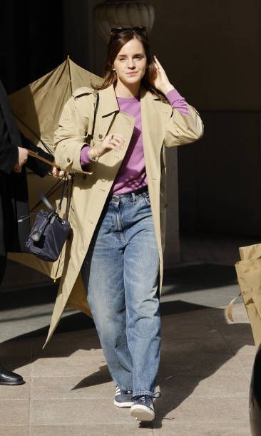 a woman is walking down the street with an umbrella in her hand and she is wearing jeans