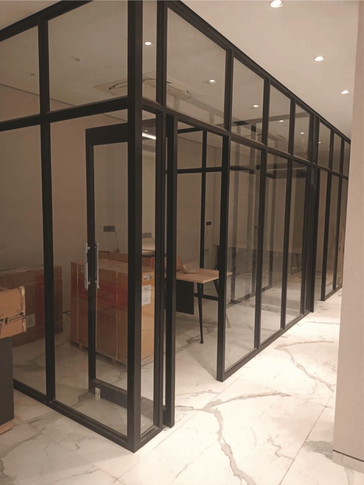 an office with glass walls and boxes on the floor