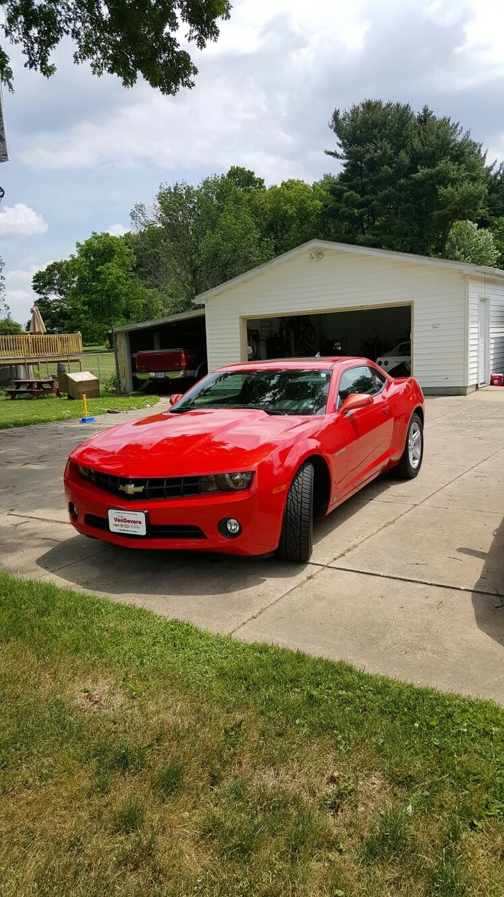 a red car parked in front of a garage