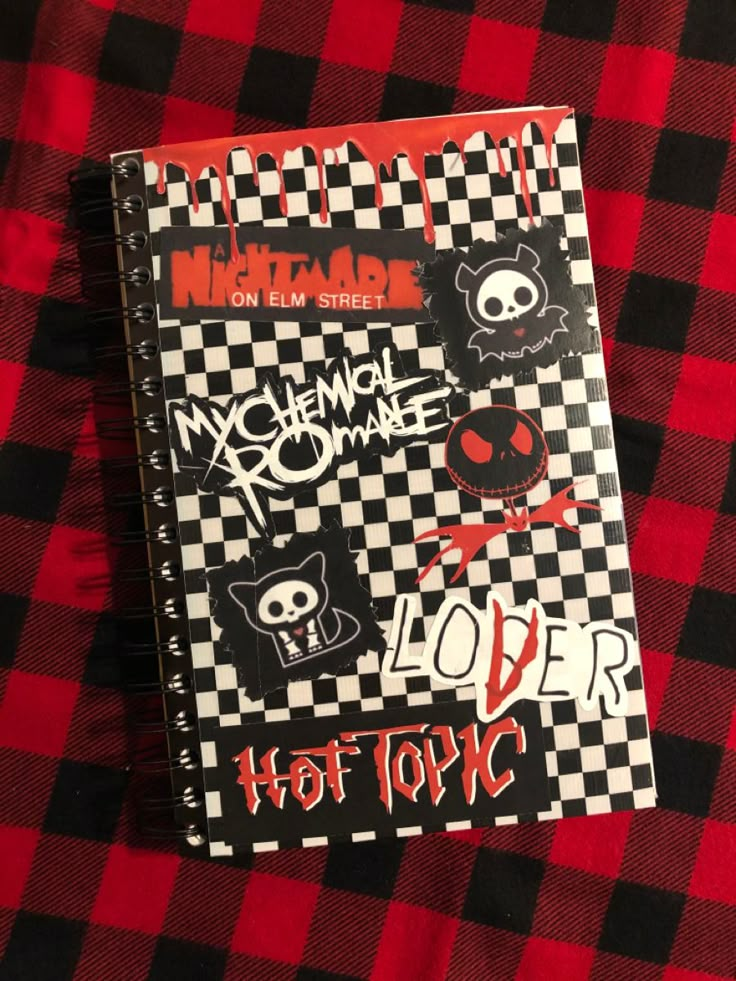 a notebook with stickers on it sitting on a red and black checkered blanket