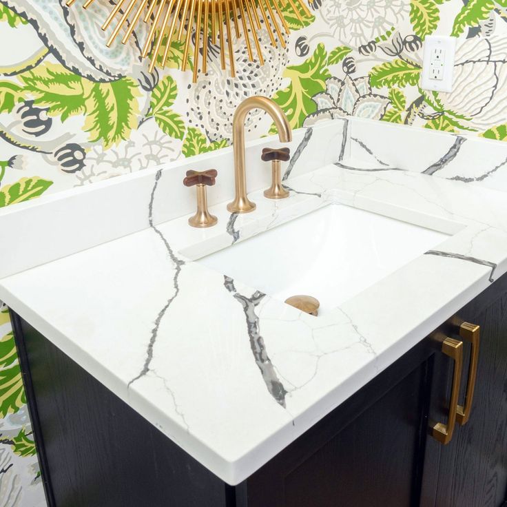 a white sink sitting under a golden faucet in a bathroom next to a mirror