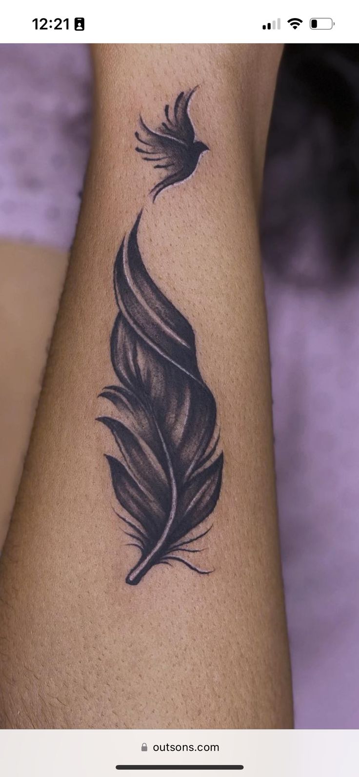 a woman's arm with a black feather tattoo on the left side of her arm