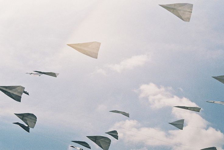 many paper airplanes are flying in the sky