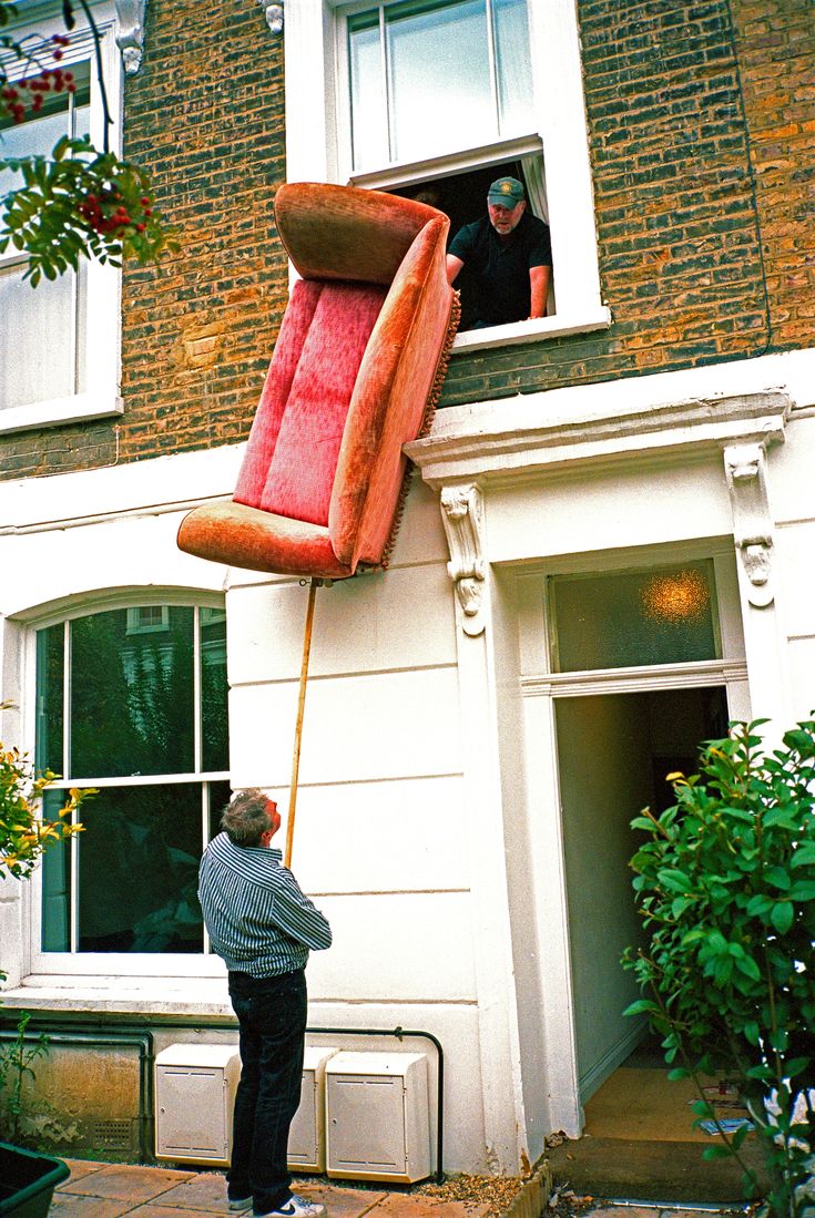 a man standing in front of a building with a giant object hanging from it's side