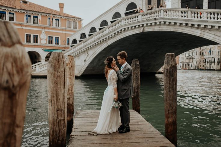 a bride and groom standing on a bridge in venice