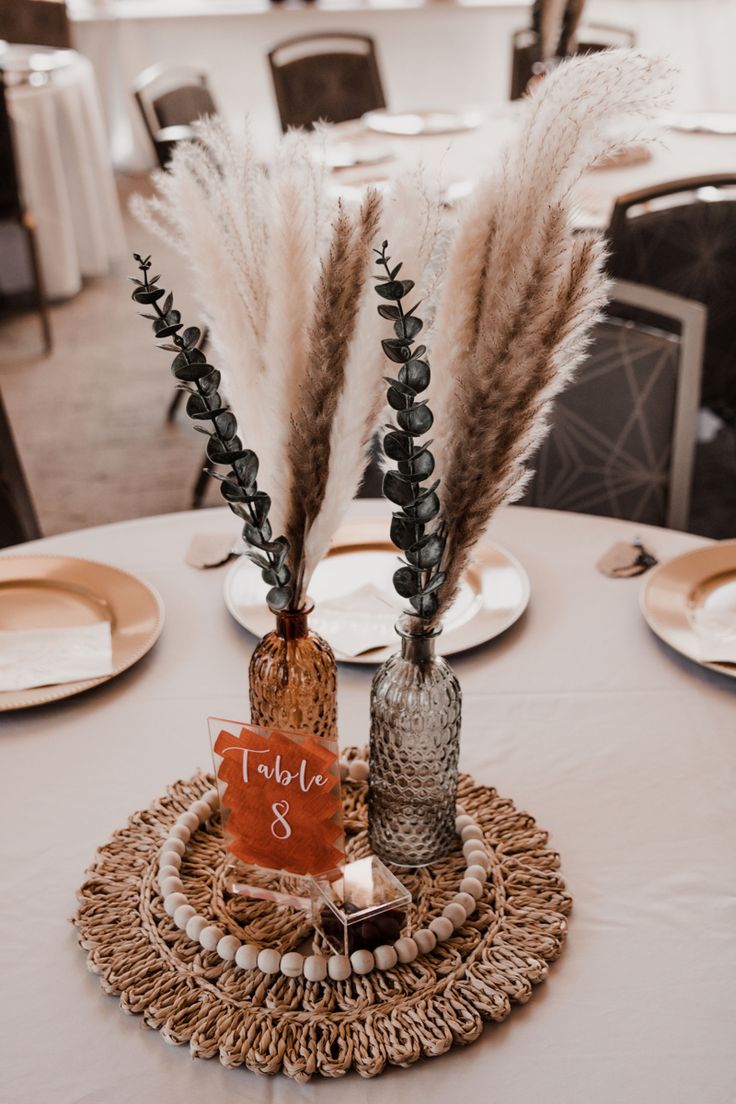 there are two vases with flowers in them on top of a round table cloth