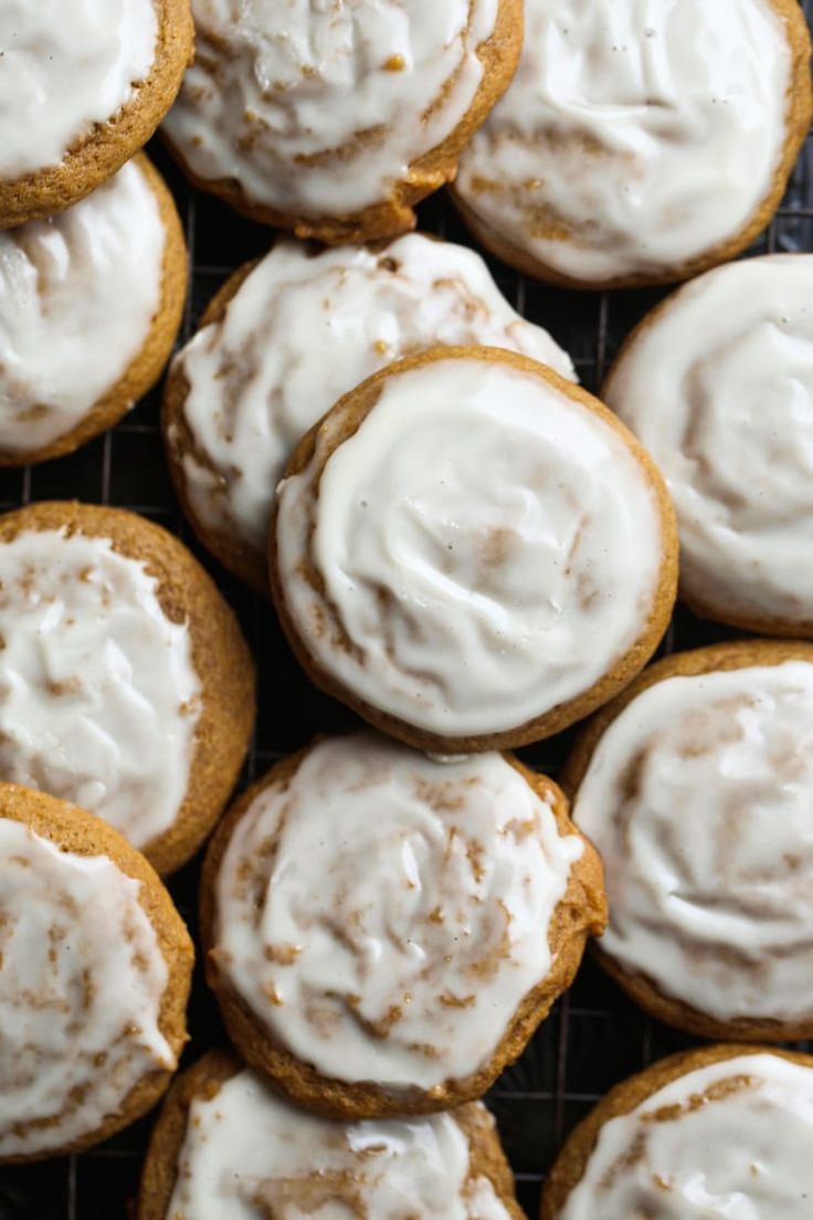 frosted cinnamon rolls sitting on top of a cooling rack with icing around them