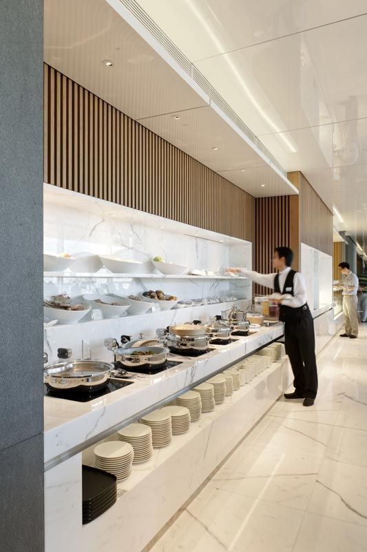 a woman standing in front of a counter filled with plates and pans on it