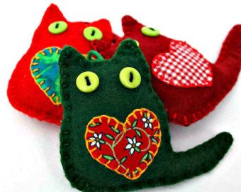 three different colored cats with green eyes and one has a red heart on its back