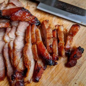 sliced bacon sitting on top of a cutting board with a knife next to it's cut ends