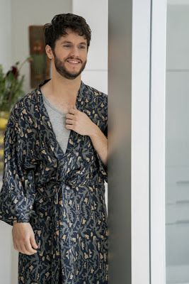 a man standing next to a wall wearing a robe