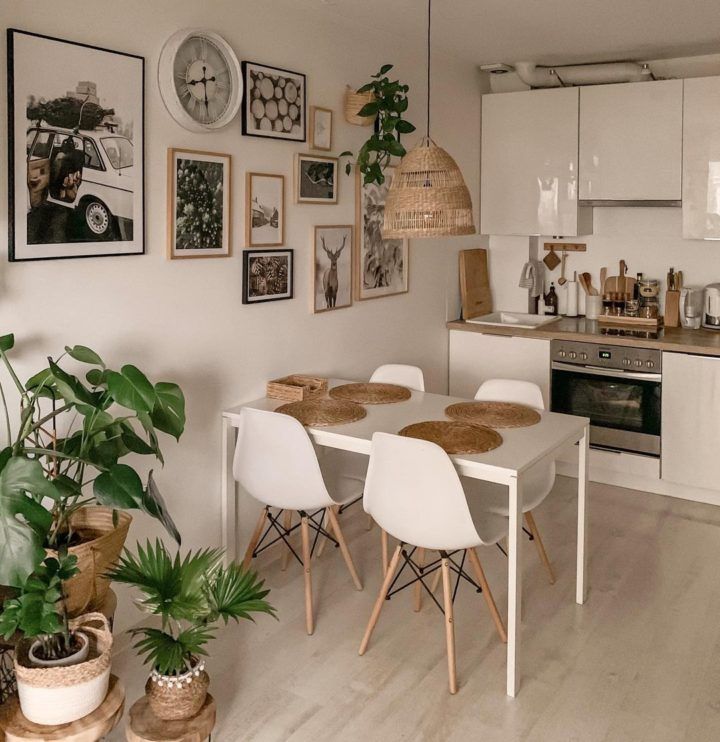 a dining room table and chairs in front of a kitchen with pictures on the wall