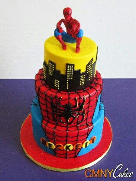 a spiderman themed cake on top of a blue tablecloth with red and yellow accents