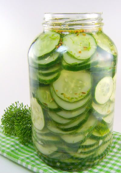 a jar filled with sliced cucumbers on top of a green checkered cloth