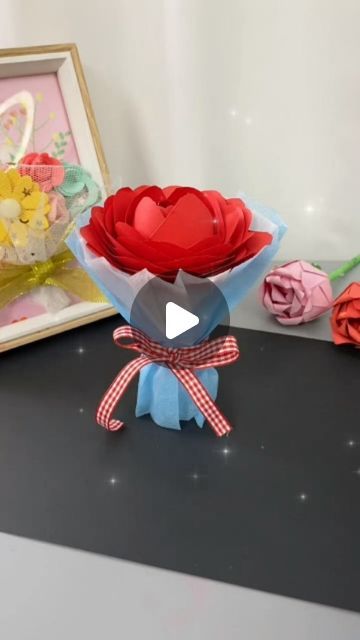 an origami flower arrangement in front of a photo frame with paper flowers on it