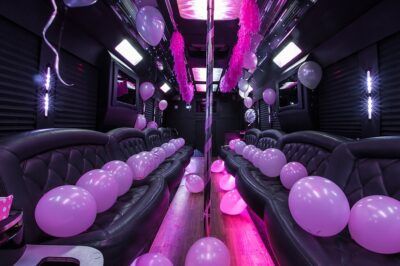 the inside of a party bus with balloons and streamers on the ceiling, along with black leather seats