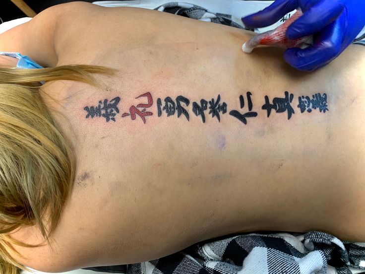 a woman with writing on her back is getting an injection