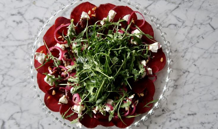 a white plate topped with radishes and other veggies on top of a marble table