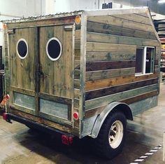 an old wooden truck with two round windows on the front and side, parked in a warehouse