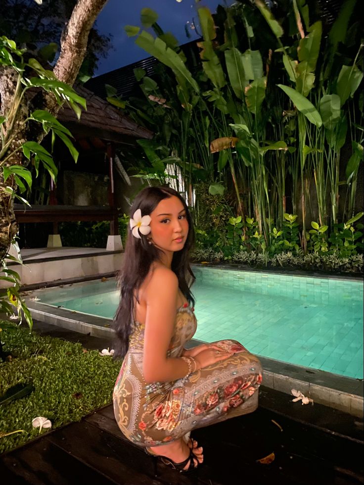 a woman sitting on the ground next to a pool