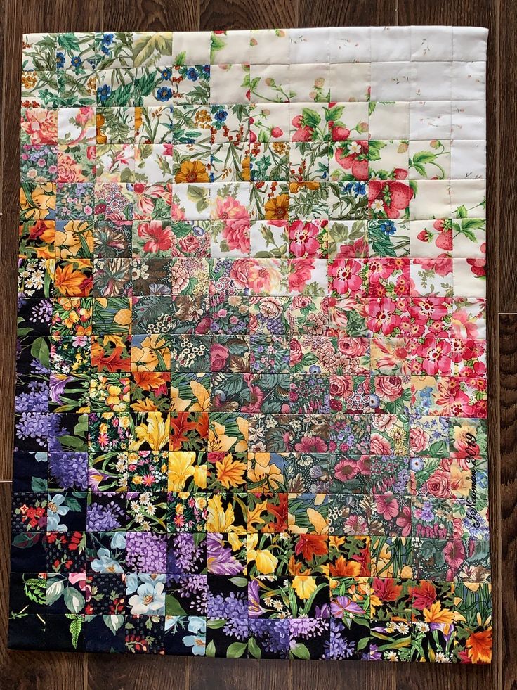 a piece of fabric with flowers on it sitting on top of a wooden floor next to a wall