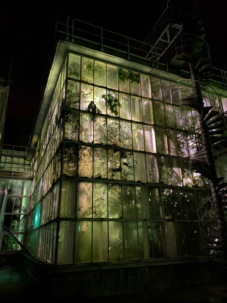 the building is lit up at night with green lights on it's windows and stairs